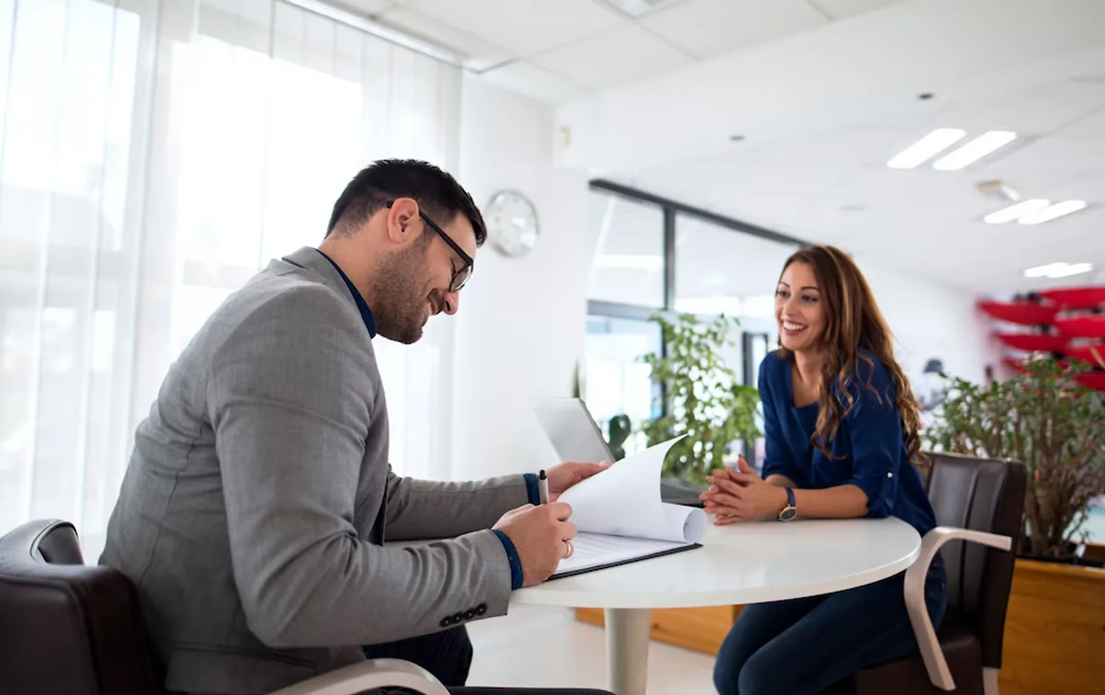 Office Workers | CAQA LLND A man and woman discuss documents at a table, demonstrating employability skills in an office setting.